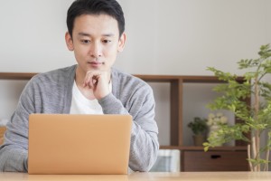 Asian,Man,Using,A,Computer,In,The,Living,Room