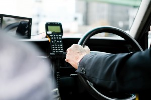 Close,Up,Old,Hand,On,Steering,Wheel,With,Electronic,Machine.
